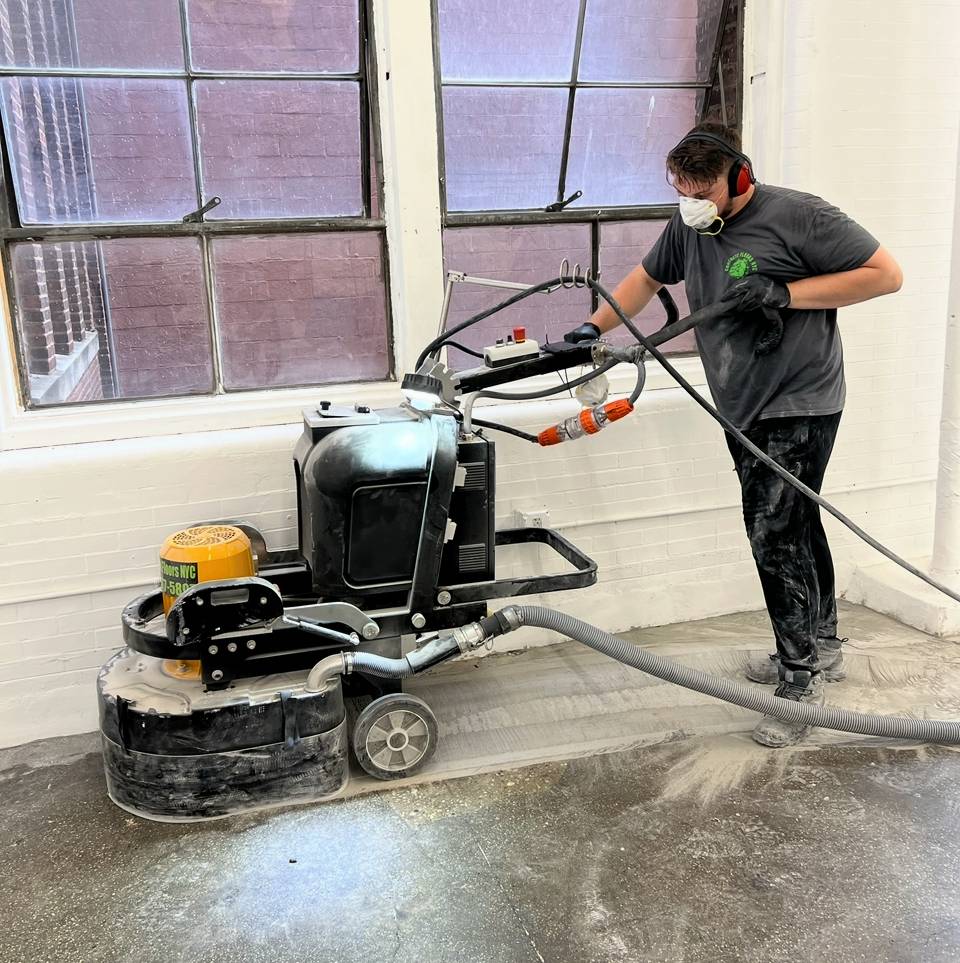 A man in black shirt holding a hose near machine.