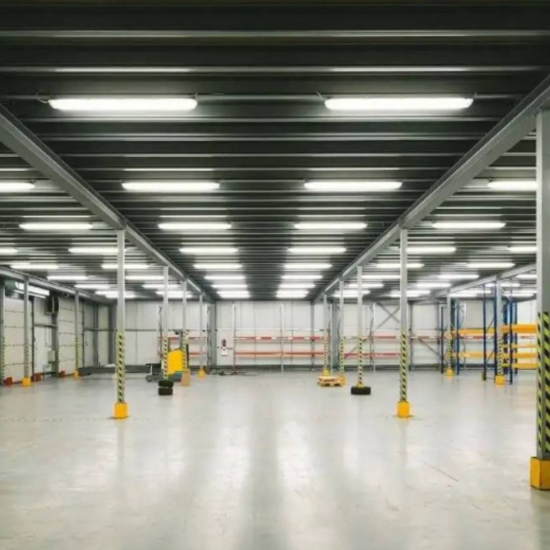 A warehouse with many lights and a yellow forklift.