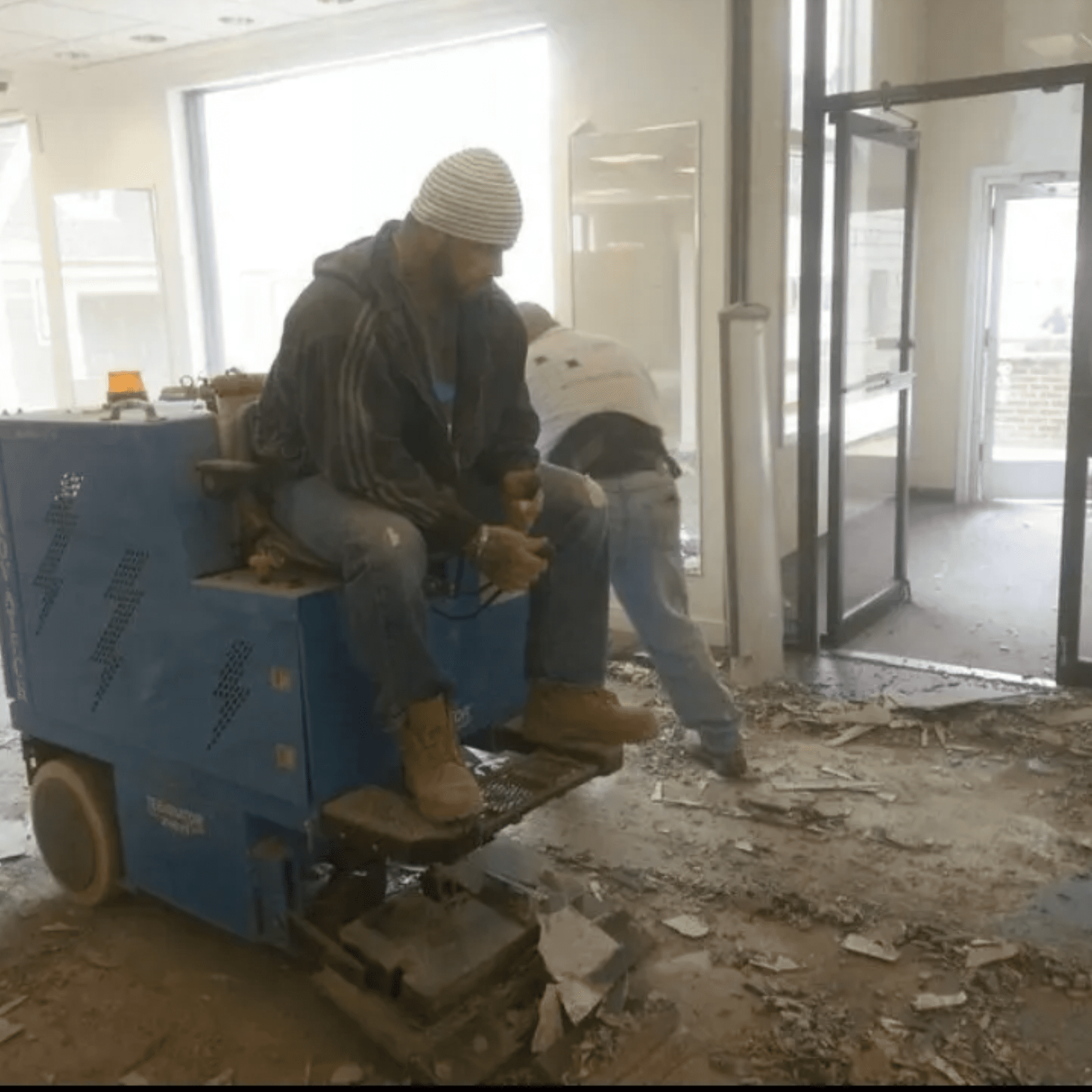 A man sitting on the back of a machine in an unfinished room.